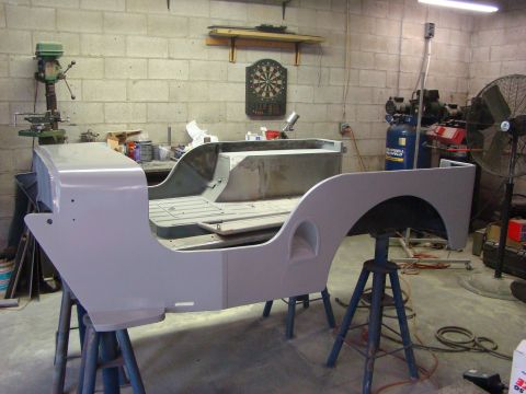 1948 Jeep Wrangler - The body of a Jeep CJ-3A is shown in a workshop, supported by stands and appearing to be prepped for painting.