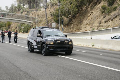 1993 Ford Taurus - Black SUV with bull horns on the hood and 'GUMBALL 3000' text on the windshield drives on a highway.
