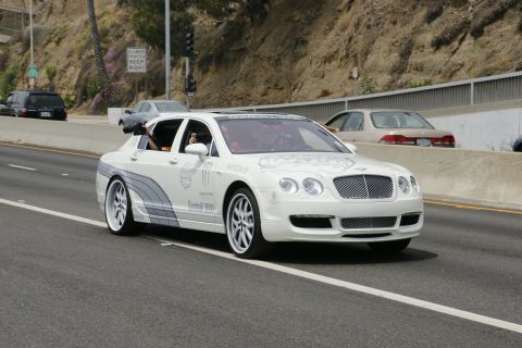 1993 Ford Taurus - A white Bentley Continental Flying Spur, adorned with custom graphics including Monster Energy logos, cruises down the highway.