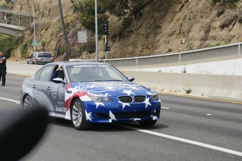 1993 Ford Taurus - A BMW M5 participates in the Gumball 3000 rally, its hood and front fenders adorned with a patriotic stars and stripes design.