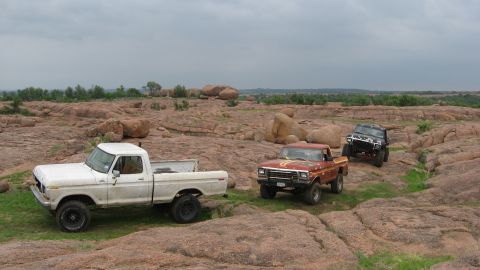 1979 Ford Bronco - Three trucks navigate a rocky landscape under a cloudy sky.