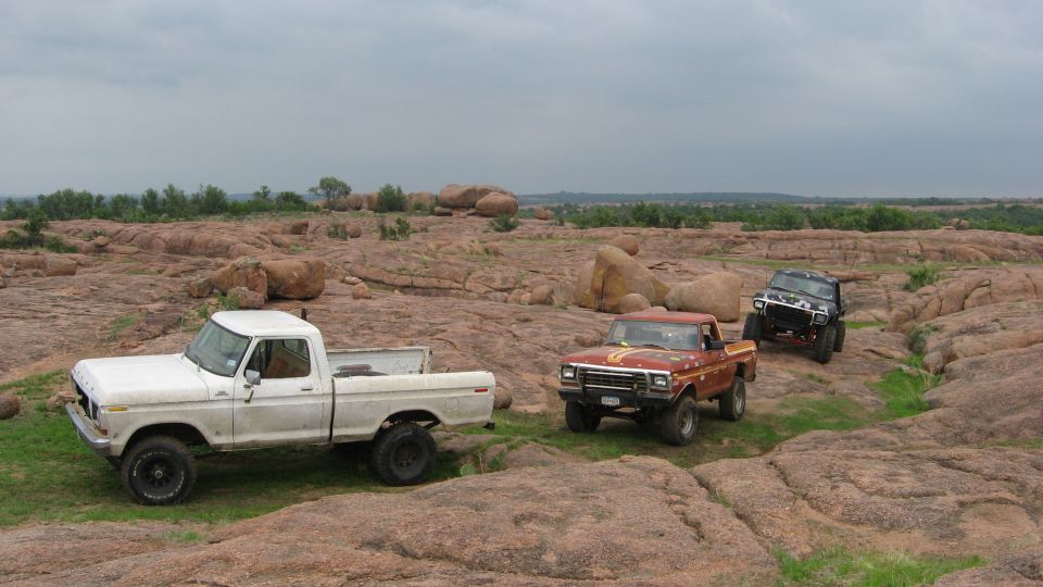 White pickup truck, red pickup truck, and black SUV on rocky terrain