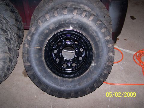 1989 Ford F-150 - Several tires are stacked, with one mounted on a black rim. An orange cord lies on the floor nearby.
