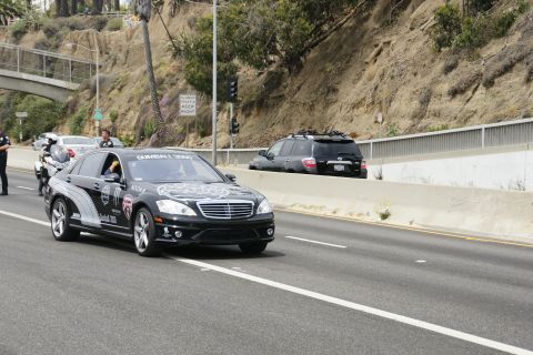 1993 Ford Taurus - A black Mercedes-Benz S-Class with Gumball 3000 livery is seen on the highway, with a black SUV in the background.