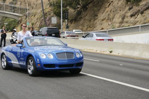 1993 Ford Taurus - A blue Bentley convertible with Gumball 3000 livery is seen on the highway, with a person standing in the passenger seat.