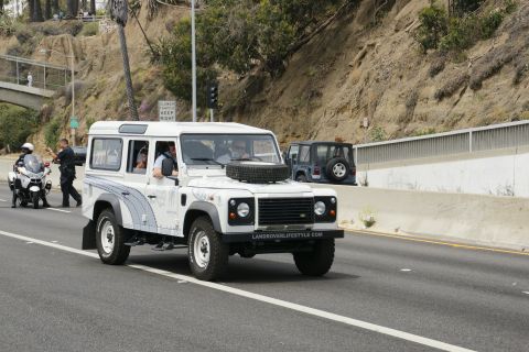 1993 Ford Taurus - A white Land Rover Defender 110 is seen driving on a road, with a police motorcycle and officer nearby.