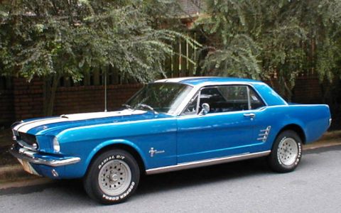 1983 Ford Bronco - A blue 1965 Ford Mustang coupe with white racing stripes is parked on the side of the road.