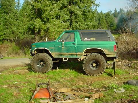 1983 Ford Bronco - Side view of a modified green Ford Bronco with large off-road tires.