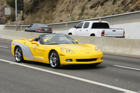 1993 Ford Taurus - Yellow convertible sports car with GUMBALL 3000 banner on windshield, driving on highway.