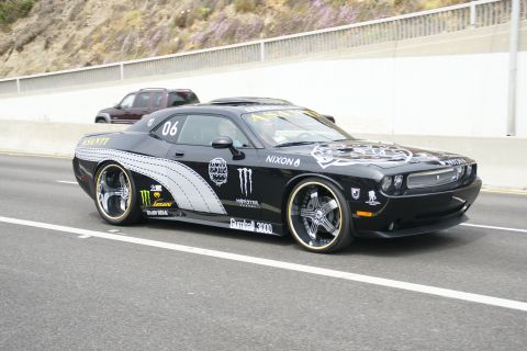 1993 Ford Taurus - A modified black Dodge Challenger with prominent racing decals drives on a highway.