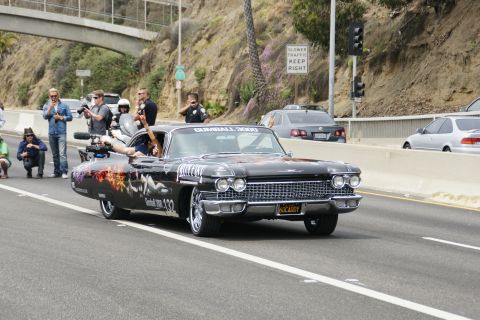 1993 Ford Taurus - A black Cadillac with elaborate custom graphics and 'Gumball 3000' branding drives on the highway.