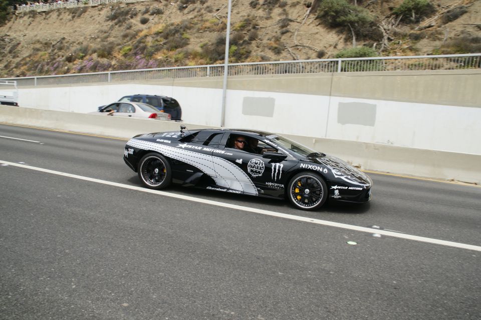 Black sports car with Monster Energy and Nixon logos, driving on a highway
