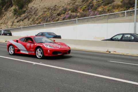 1993 Ford Taurus - A red Ferrari with racing decals drives on a highway alongside other vehicles.