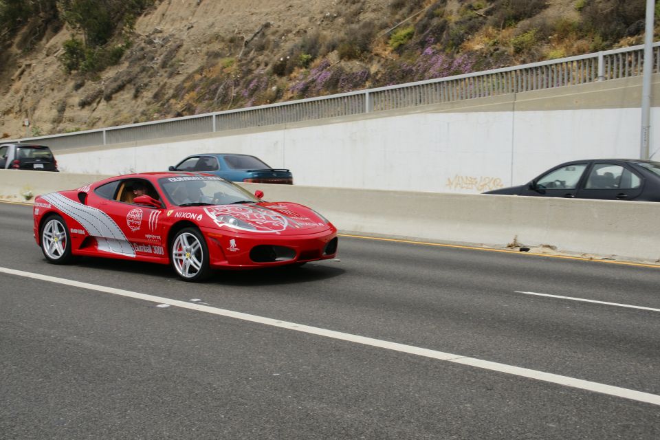 Red Ferrari with racing decals and sponsor logos on the side, driving on a highway