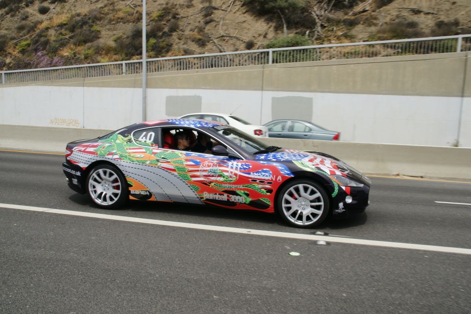 Sports car with elaborate graphics, including dragons and flags, driving on a highway. Number 40 visible on the door