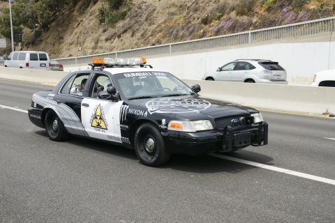 1993 Ford Taurus - A modified police car with custom decals drives on the highway.