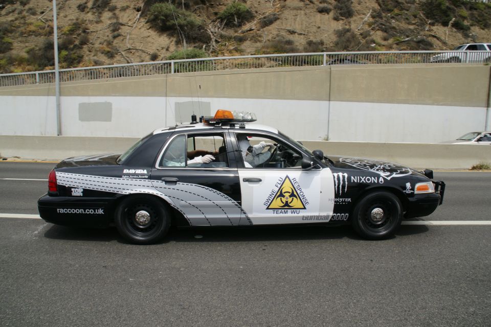 Black and white police car with graphics, siren, and light bar, seen from the side