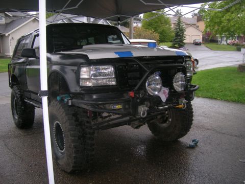 1996 Ford Bronco - Modified black Ford Bronco with off-road tires and custom front bumper is parked under a canopy.