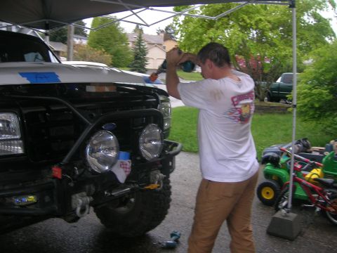1996 Ford Bronco - A man works on the hood of a black Ford Bronco, which has a custom bumper and auxiliary lights.