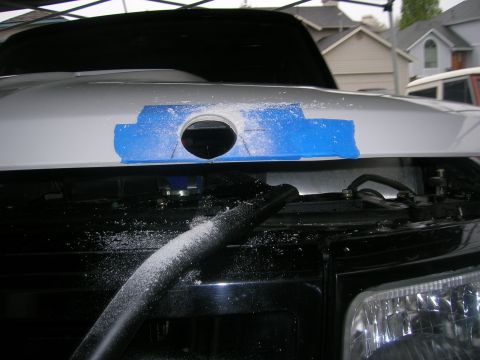 1996 Ford Bronco - Cutting a hole in a vehicle hood, with sawdust and blue tape visible.