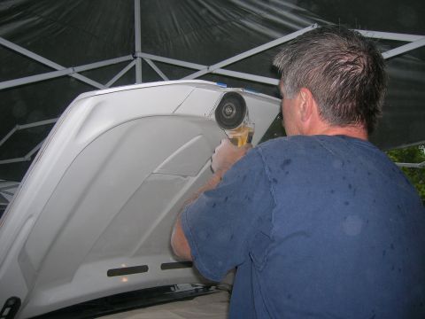 1996 Ford Bronco - Man modifies a car hood with an angle grinder.