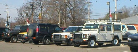 1983 Ford Bronco - Multiple SUVs are parked in an outdoor lot under a bright sky.