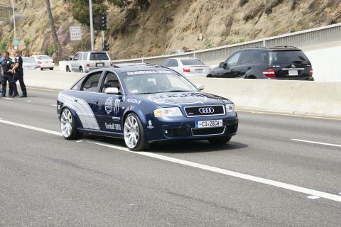 1993 Ford Taurus - An Audi A6 participates in the Gumball 3000 rally, with police officers present on the roadside.