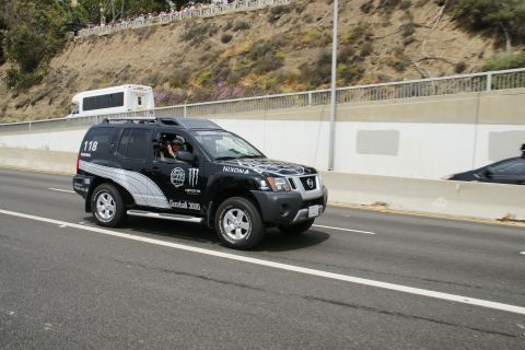 1993 Ford Taurus - A black SUV with racing decals drives down a highway, with a white bus visible in the background.