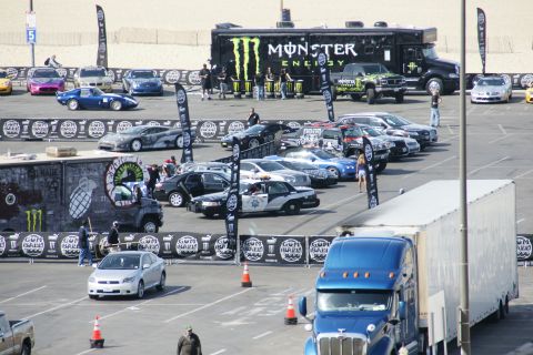 1993 Ford Taurus - A variety of vehicles are gathered, including a Monster Energy truck and a police car, with a beach in the background.