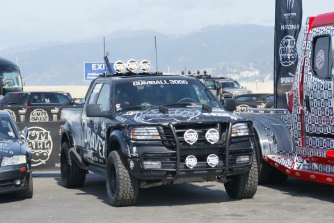 1993 Ford Taurus - A modified black pickup truck with Gumball 3000 branding is parked alongside other vehicles.