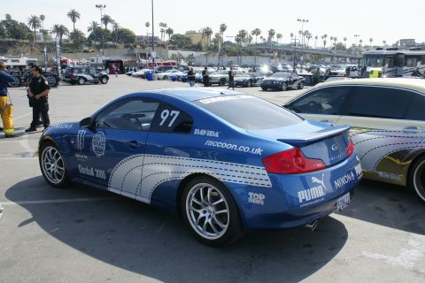 1993 Ford Taurus - Blue Infiniti G35 coupe with racing decals and number 97 is parked next to another car.