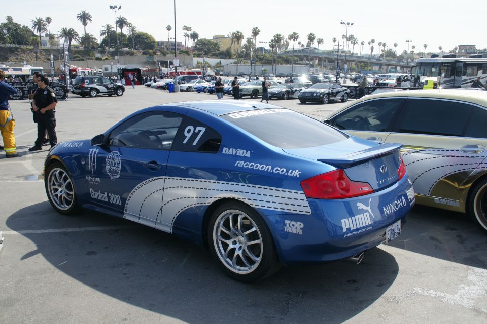 Blue Infiniti G35 coupe with racing decals, number 97 on door, parked next to a gold car