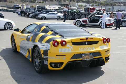1993 Ford Taurus - A yellow Ferrari with racing decals and a distinctive stripe pattern is parked in a lot with other vehicles.