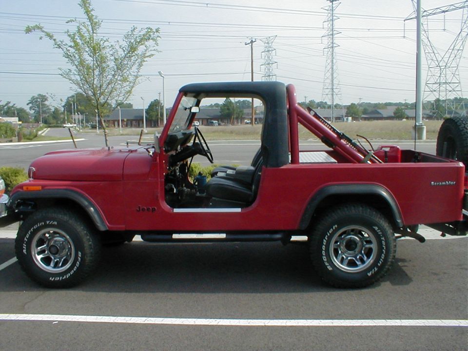 Red Jeep Scrambler pickup, side view, doors off, black roll bar, BFG tires