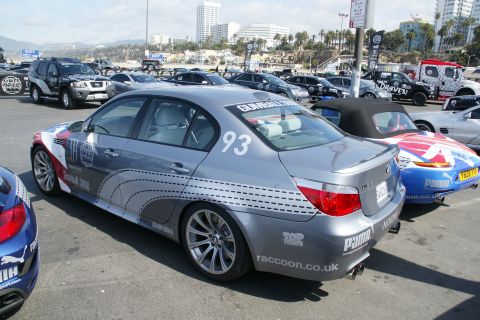 1993 Ford Taurus - A silver BMW sedan, number 93, participates in the Gumball 3000 rally, parked alongside other vehicles.
