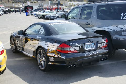 1993 Ford Taurus - A black Mercedes-Benz SL63 AMG with racing decals is parked in a lot.