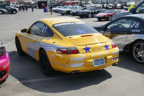 1993 Ford Taurus - A yellow Porsche Carrera with Gumball 3000 and Puma livery is parked next to another car.