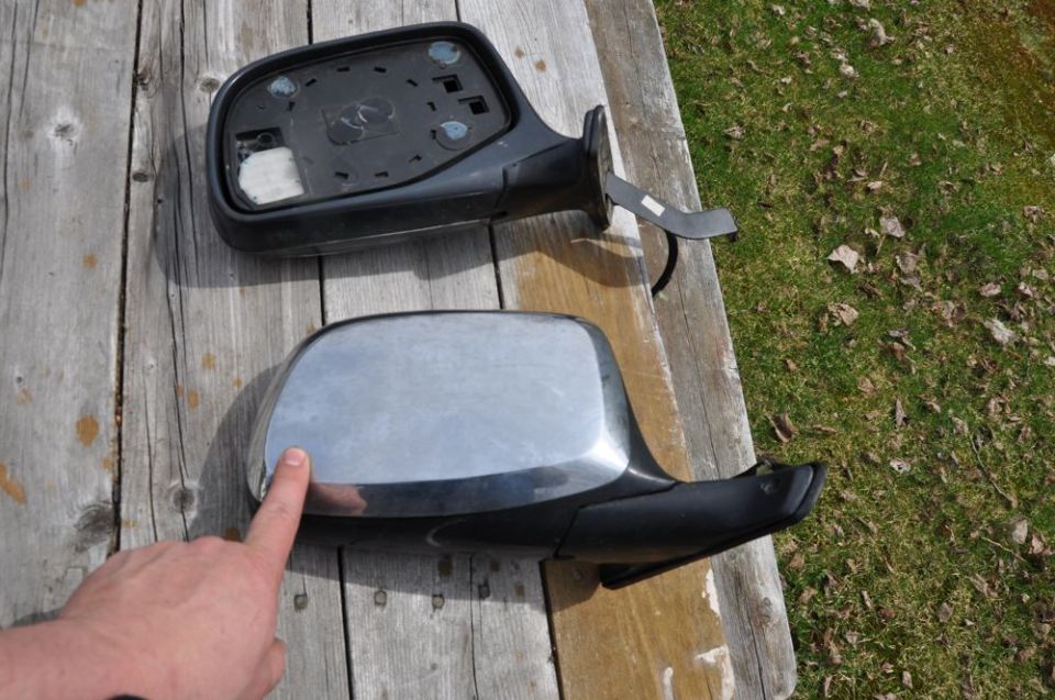 Two side mirrors on weathered wood, one chrome and one black