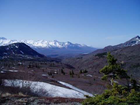2000 Ford E350 - A wide-angle view of a vast mountain landscape under a clear blue sky. Snow-capped peaks stretch across the horizon, with rolling, treeless…