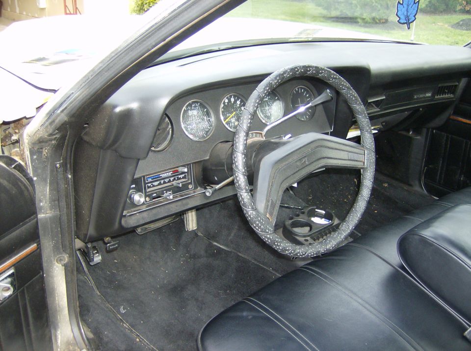Black car interior with wrapped steering wheel, round gauges and center radio