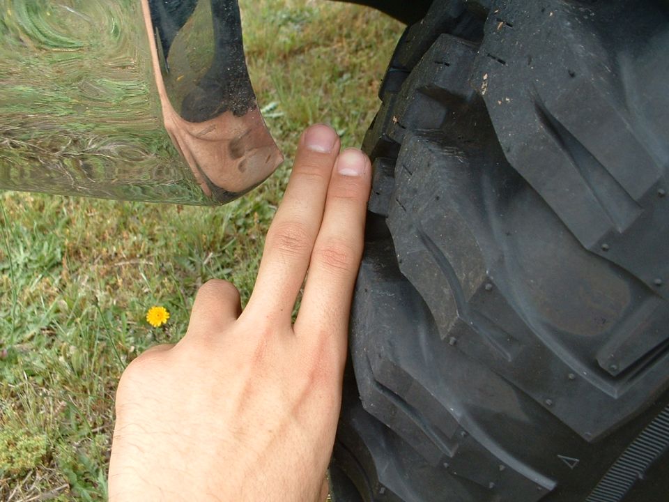 Two fingers measuring clearance between chrome bumper and off-road tire tread