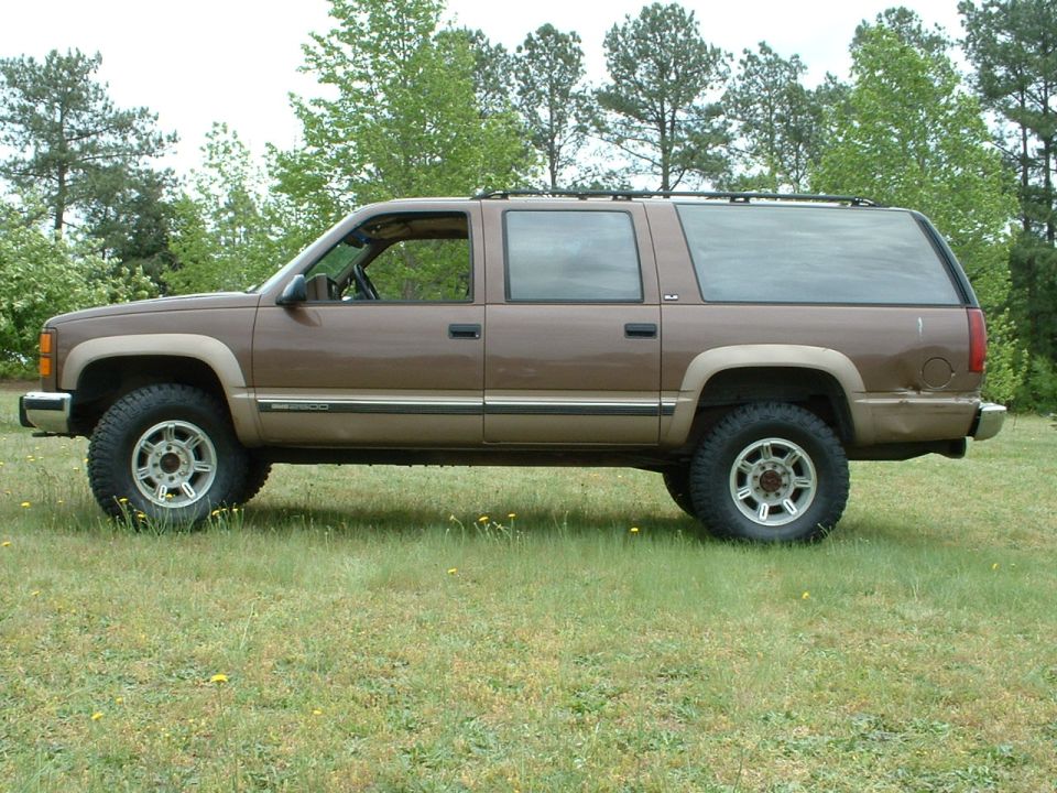 Brown two-tone GMC Suburban 2500 side profile in a field