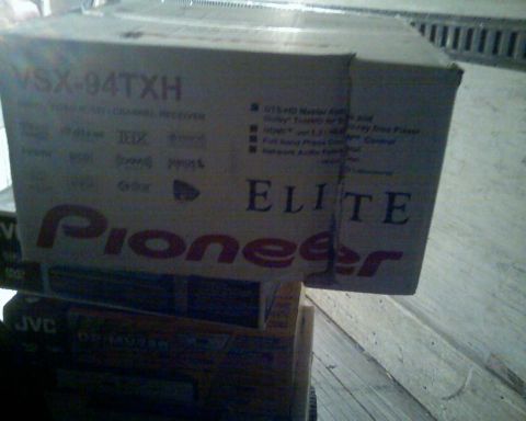 2006 Ford E350 - A close-up of a cardboard box for a Pioneer Elite VSX-94TXH AV Receiver, stacked on top of other boxes. The box is mostly white with red an…