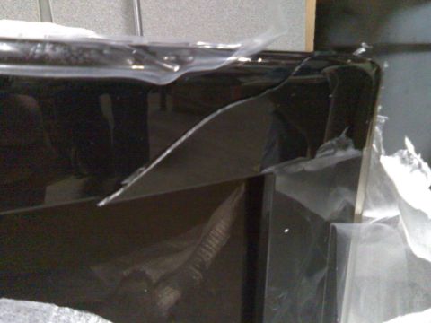 2006 Ford E350 - A close-up, angled shot shows the corner of a dark, reflective vehicle panel, possibly a door or fender, covered in protective plastic wrap…