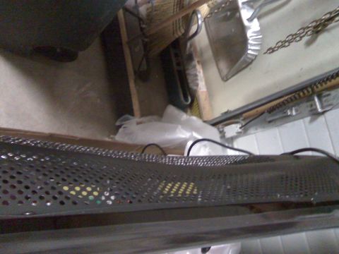 2006 Ford E350 - A close-up view of a perforated metal surface with some colorful items visible behind it. In the background, a dustpan and broom are leanin…