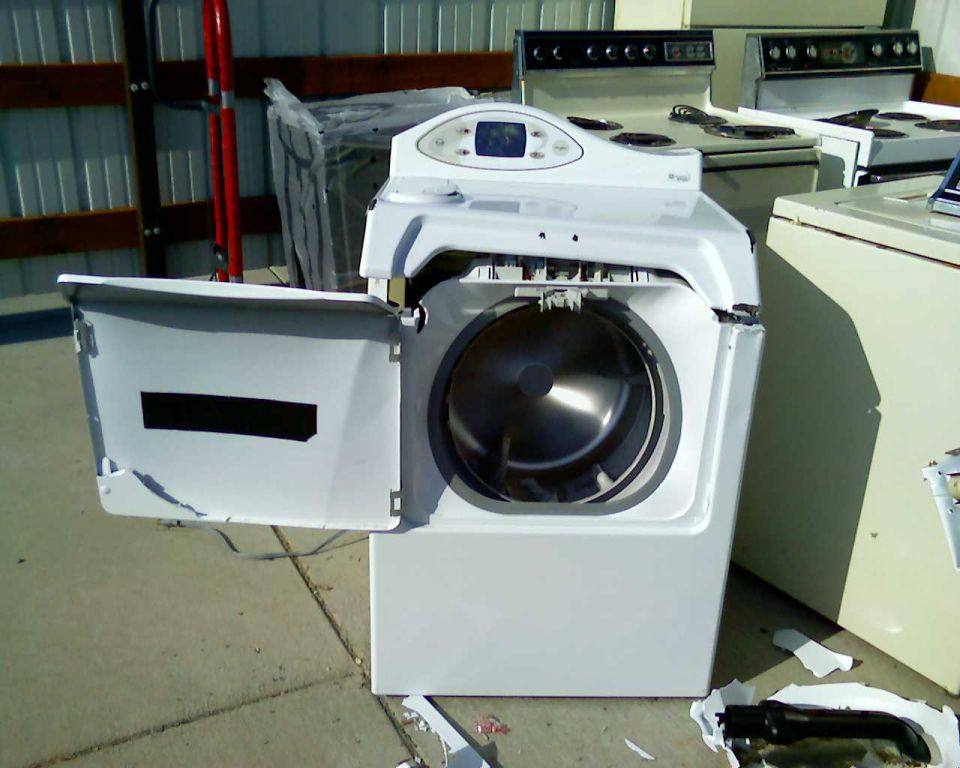 Damaged white front-loading washing machine with its door open.