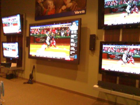 2006 Ford E350 - Multiple televisions are mounted on a wall, displaying sports games. One television shows a baseball game with players on the field and a "…