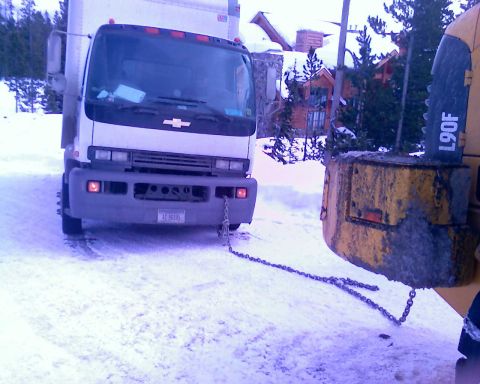 2006 Ford E350 - A white box truck is parked in the snow, attached by a chain to a yellow piece of heavy equipment. The truck's license plate reads "4C-9659…