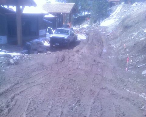 2006 Ford E350 - A silver pickup truck is parked on a muddy construction site with a building under construction in the background.