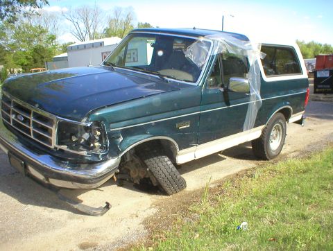 1983 Ford Bronco - This damaged Ford Bronco has a detached front passenger wheel and plastic covering the driver's side window.